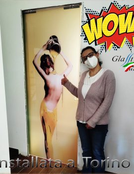 Porta scorrevole in vetro decorato con un design artistico che rappresenta una figura femminile in tonalità gialle, ideale per interni moderni.