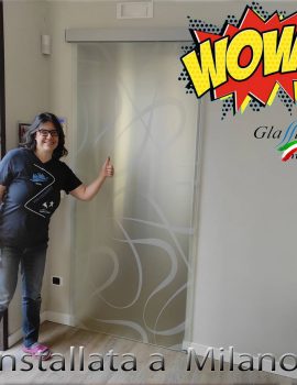 Porta scorrevole in vetro decorata con un'opera d'arte colorata in un ambiente interno.